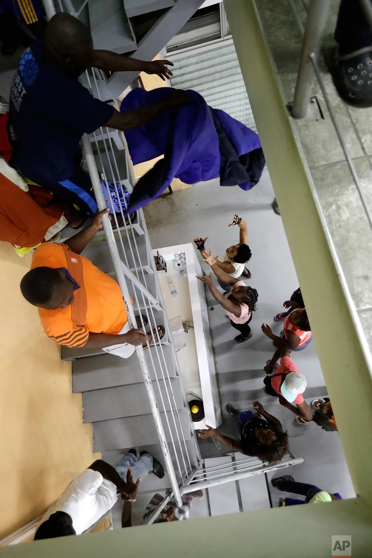 In this Sept. 26, 2016 photo, Haitian migrants toss down blankets to family members below at the Padre Chava migrant shelter, in Tijuana, Mexico. When full the shelter accommodates about 300 people, about half of them women and children. Many sleep on floors without mattresses. (AP Photo/Gregory Bull)