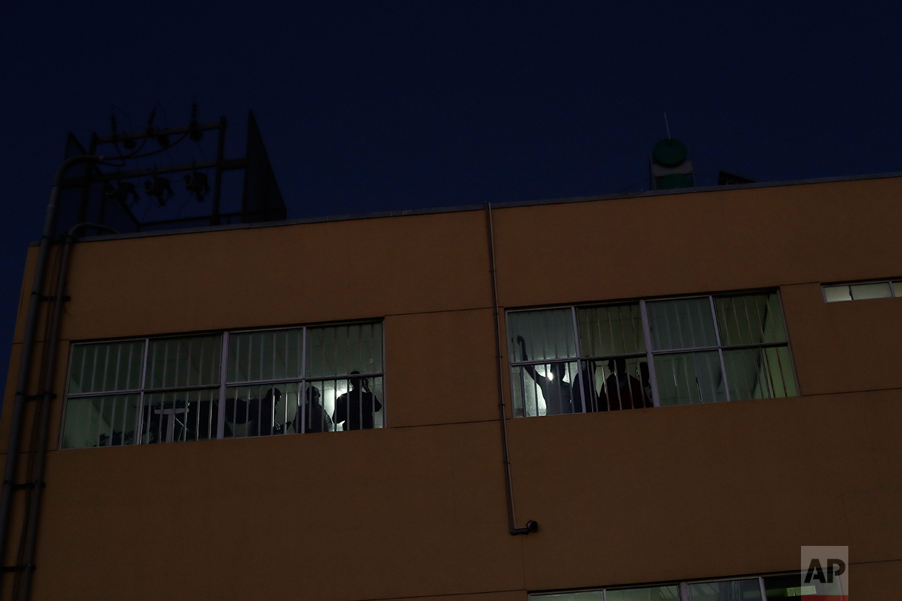 In this Oct. 3, 2016 photo, Haitian migrants look out from the sleeping quarters of the Padre Chava migrant shelter in Tijuana, Mexico. When full, the shelter can accommodate about 300 people with many sleeping on floors without mattresses. (AP Photo/Gregory Bull)