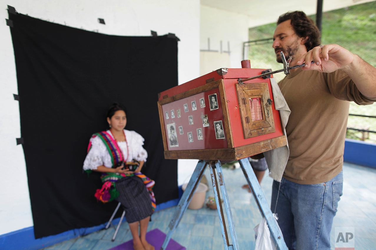In this Aug. 8, 2011 photo, Associated Press photographer Rodrigo Abd uses a 19th-century style wooden box camera as he photographs a participant of the Rabin Ajau National Folkloric Festival in Guatemala City. Participants had to hold still for up to two minutes as Abd made exposures with light shining directly from the lens onto photo paper inside the box camera. (AP Photo/Jesus Cuque Lopez)