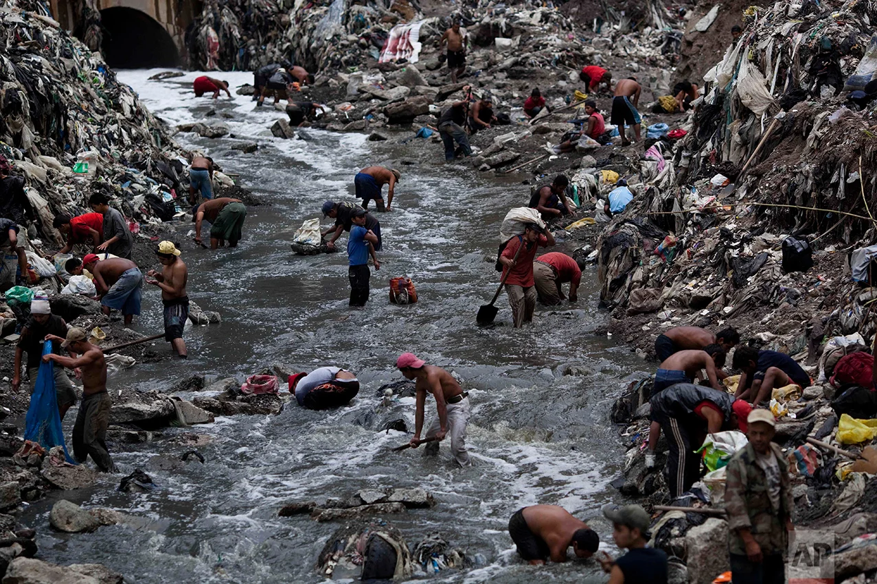  In this Oct. 19, 2011 photo, people search for scrap metal in contaminated water at the bottom of one of the biggest trash dumps in the city, known as "The Mine," in Guatemala City. (AP Photo/Rodrigo Abd)