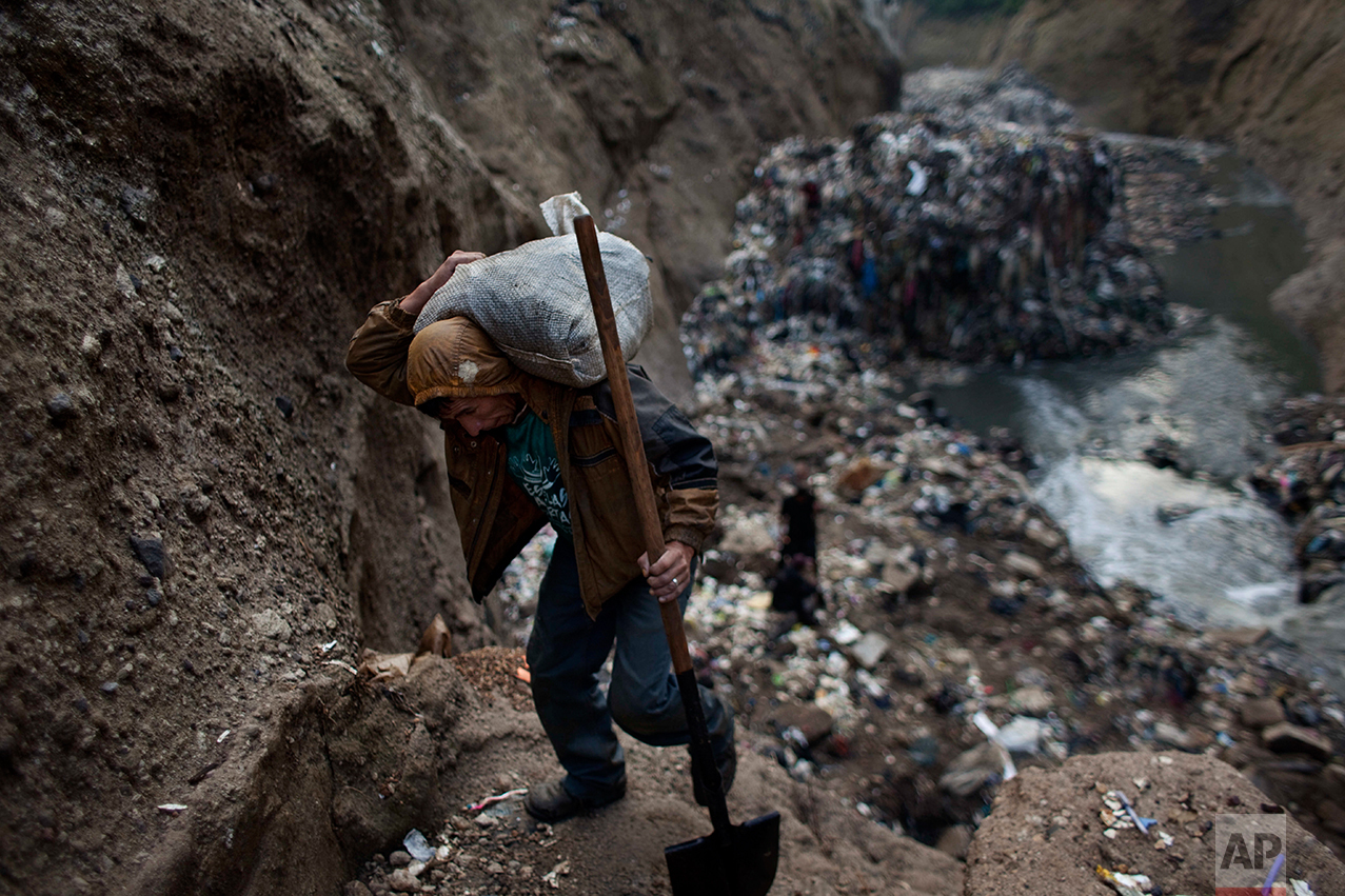  In this Oct. 5, 2011 photo, a man who only gave his first name Wilmer carries a sack of metal he collected after working the entire day at the bottom of one of the biggest trash dumps in the city, known as "The Mine," in Guatemala City. This activity known locally as "mining" is extremely dangerous due to mud slides and collapses, but earns many of them about 150 quetzals ($20 dollars) a day, nearly twice the minimum daily wage. (AP Photo/Rodrigo Abd)