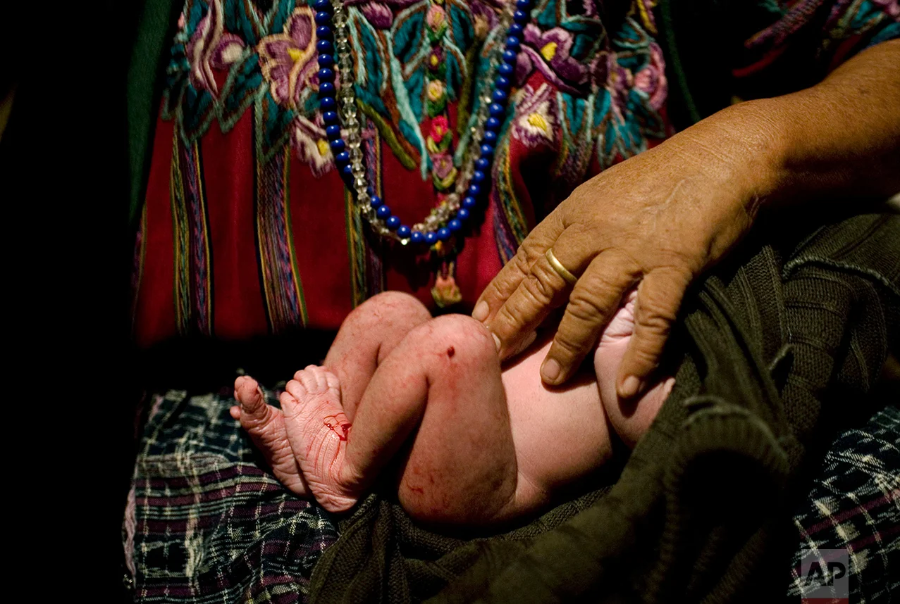 In this Sept. 10, 2008 photo, rural midwife Francisca Raquec holds Sara Raquec's newborn son in El Llano, Guatemala. In Guatemala, rural midwives deliver six of every ten babies, and the government plans to train 15,000 of them to reduce the number of women who die from child birth. (AP Photo/Rodrigo Abd)