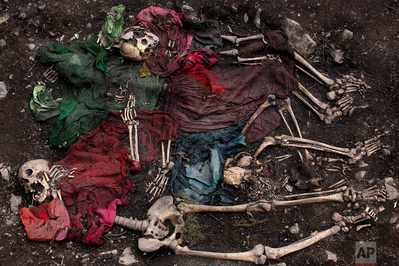  In this Nov. 13, 2013 photo, the scattered remains of five skeletons are unearthed during an exhumation of a mass grave in the district of Chungui, Peru. This isolated corner of Peru is witnessing the biggest exhumation to date of victims of the nation's 1980-2000 internal conflict, which claimed an estimated 70,000 lives. (AP Photo/Rodrigo Abd)