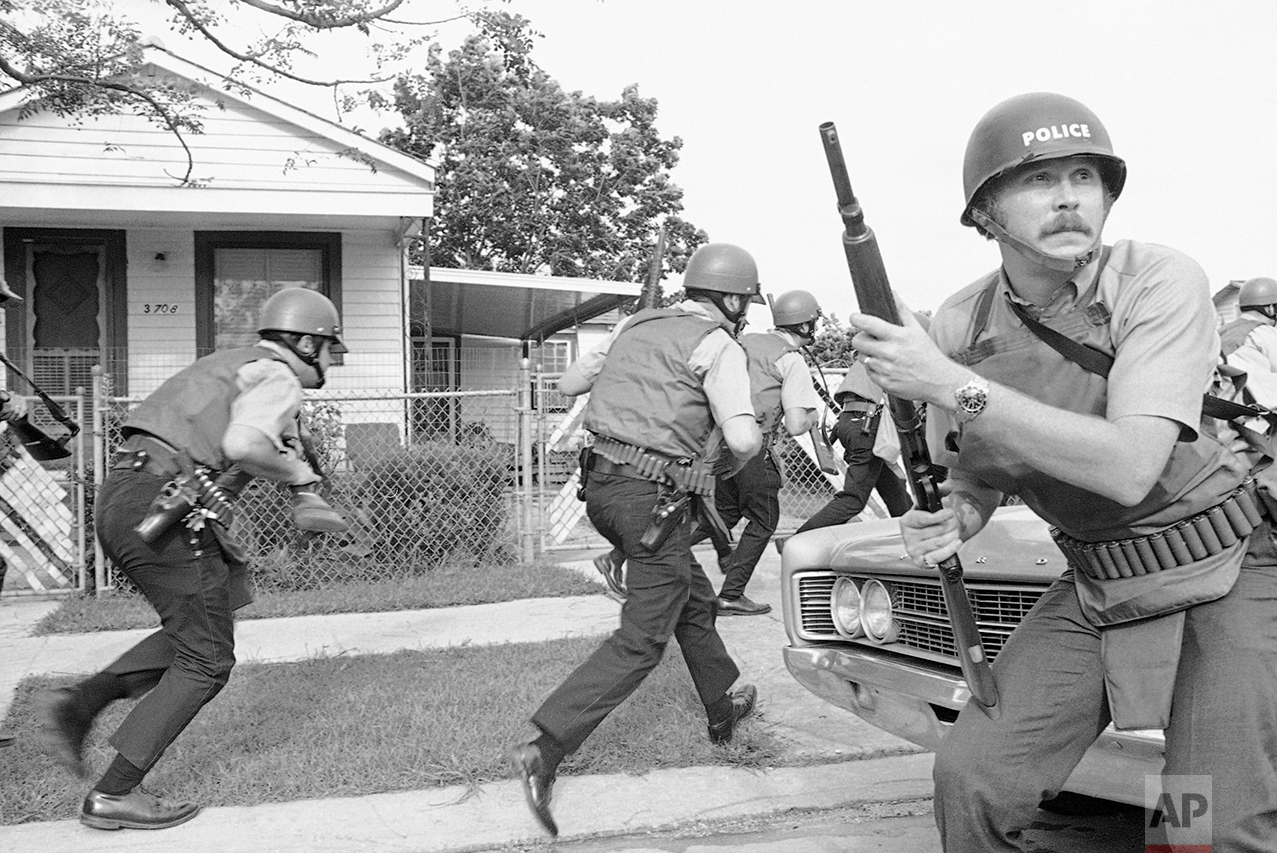 New Orleans police officers try to keep their heads down as they move in on a Black Panther headquarters during an exchange of gunfire in New Orleans on Sept. 15, 1970. (AP Photo/Jack Thornell)