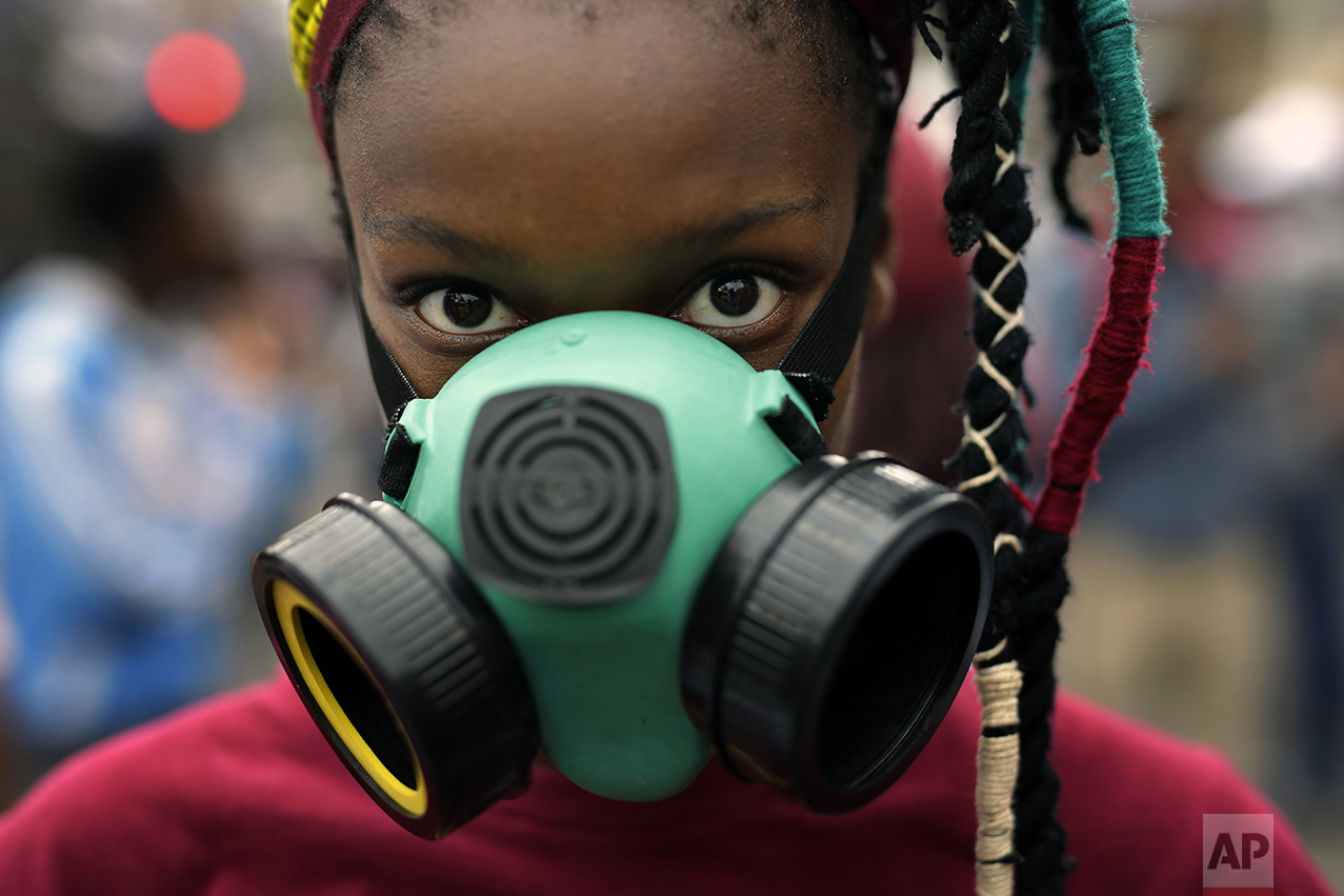 A student wears a mask as she and others demonstrate in downtown Pretoria, South Africa, Thursday, Oct. 20, 2016. The students were granted last minute permission to walk to the Union Building. Protests calling for free education have sometimes turned violent, and have affected many South African universities since last month. (AP Photo/Jerome Delay)