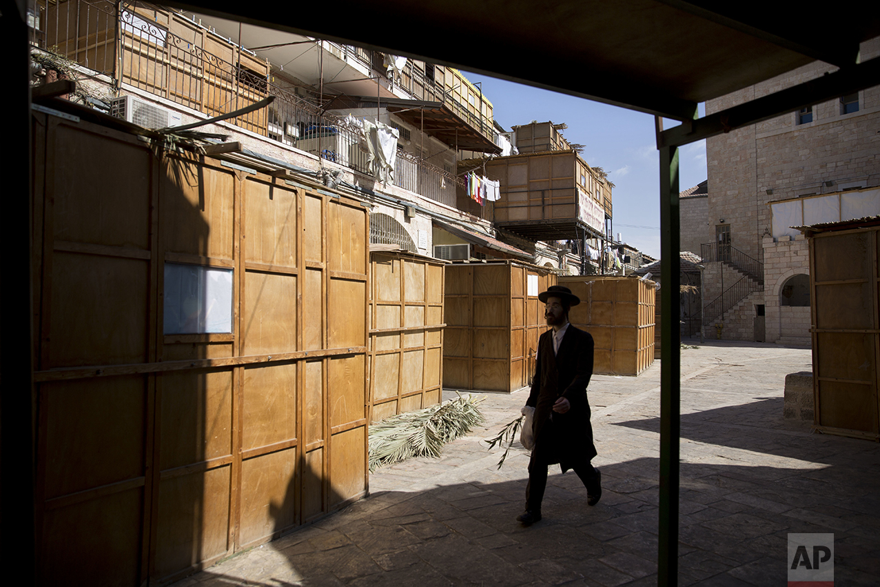 An ultra-Orthodox Jewish man walks next to sukkahs, temporary structures built for the Jewish holiday of Sukkot, in Jerusalem, Sunday, Oct. 16, 2016. The huts commemorate the temporary, portable dwellings in which Jewish people lived during their 40-year sojourn in the wilderness that followed their liberation from slavery in Egypt. (AP Photo/Sebastian Scheiner)