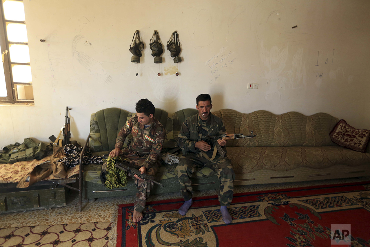 Iraqi Kurdish Peshmerga fighters clean their weapons outside Bartella, Iraq, Friday, Oct. 21, 2016. By Thursday, the Iraqi forces had advanced as far as Bartella, a historically Christian town some nine miles (15 kilometers) from Mosul's outskirts. (AP Photo/ Khalid Mohammed)