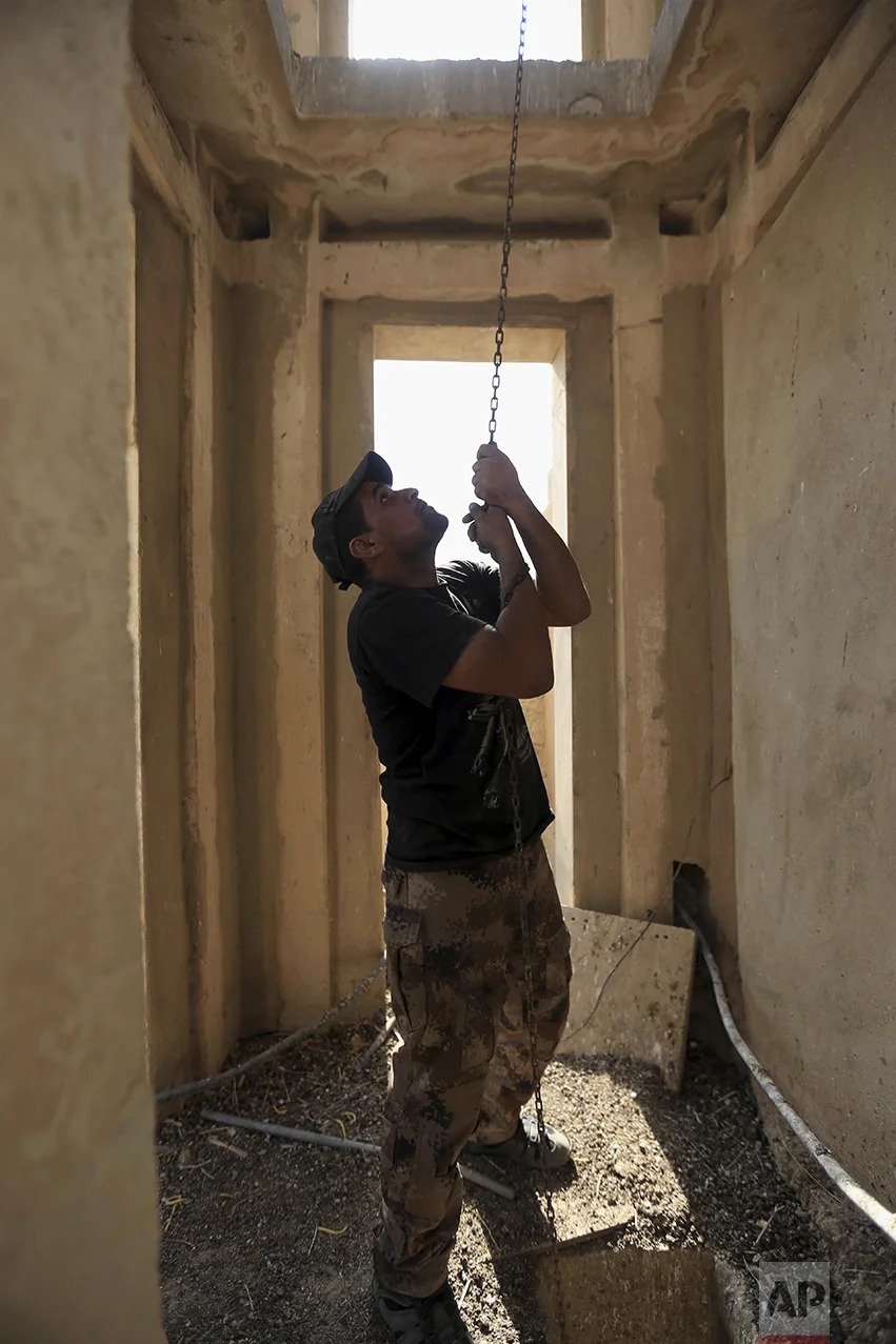 A member of Iraq's elite counterterrorism rings the bell in the church of Saint Shmoni, damaged by Islamic State fighters, in Bartella, Iraq, Sunday, Oct. 23, 2016. Iraqi forces captured Bartella, around 15 kilometers (9 miles) east of Mosul. (AP Photo/Khalid Mohammed)