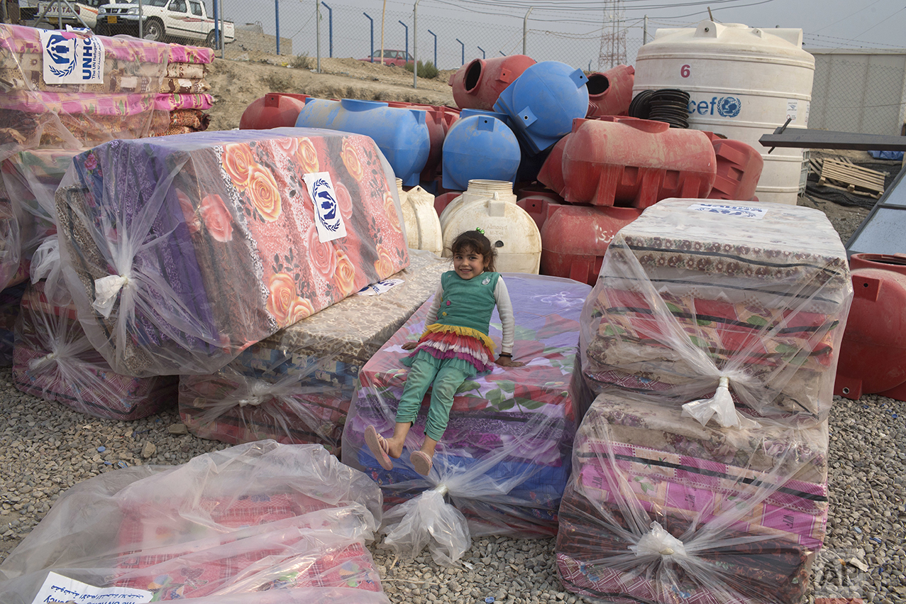 A girl sits on a pile of mattresses at a camp for displaced families in Dibaga, near Mosul, Iraq, Monday, Oct. 24, 2016. The campaign to retake Mosul comes after months of planning and involves more than 25,000 Iraqi troops, Kurdish forces, Sunni tribal fighters and state-sanctioned Shiite militias. It is expected to take weeks, if not months, to drive Islamic State militants out of Iraq's second largest city, which is still home to more than a million people. (AP Photo/Marko Drobnjakovic)