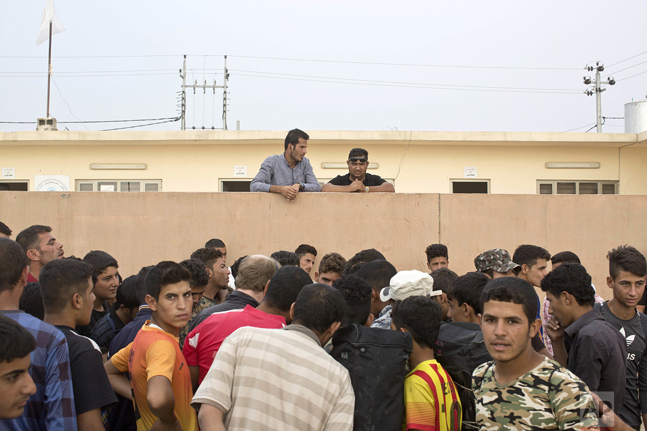 People gather as aid is being distributed at a camp for displaced families in Dibaga, near Mosul, Iraq, Monday, Oct. 24, 2016. The campaign to retake Mosul comes after months of planning and involves more than 25,000 Iraqi troops, Kurdish forces, Sunni tribal fighters and state-sanctioned Shiite militias. It is expected to take weeks, if not months, to drive Islamic State militants out of Iraq's second largest city, which is still home to more than a million people. (AP Photo/Marko Drobnjakovic)