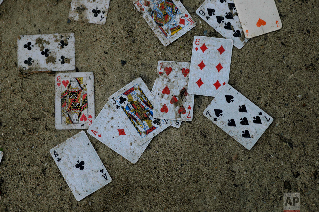In this Thursday, Oct. 27, 2016 photograph, playing cards lay abandoned outside a shelter in the makeshift migrant camp known as "the jungle" near Calais, northern France. (AP Photo/Matt Dunham)