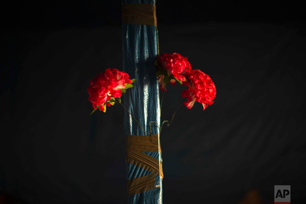 In this Tuesday, Oct. 25, 2016 photo, plastic flowers are tied with tape to a pole of an abandoned tent at the makeshift migrant camp known as "the jungle" near Calais, northern France. (AP Photo/Emilio Morenatti)