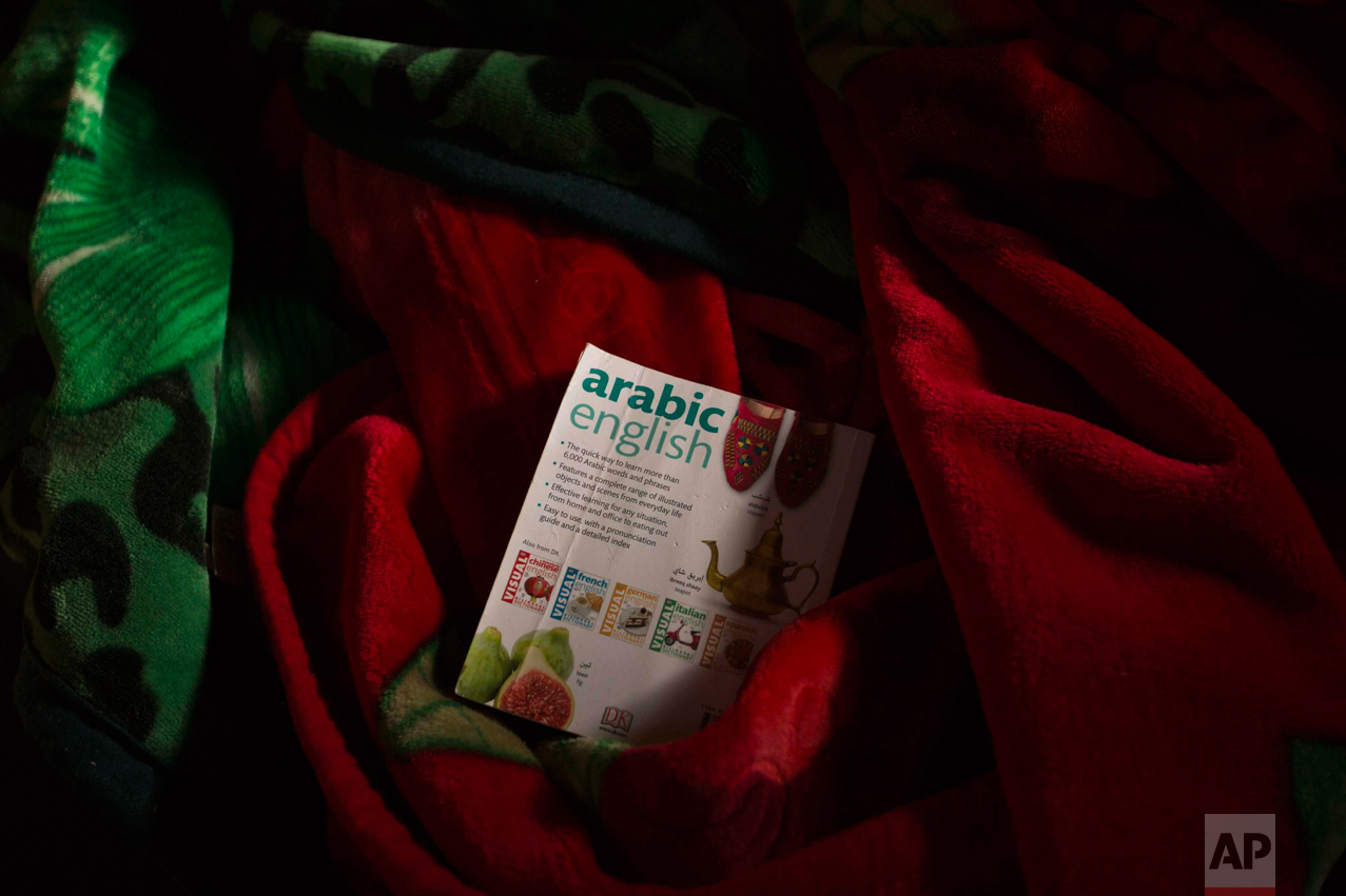 In this Thursday, Oct. 27, 2016 photo, a dictionary remains over other belongings left behind by migrants in an abandoned tent at the makeshift migrant camp known as "the jungle" near Calais, northern France. (AP Photo/Emilio Morenatti)