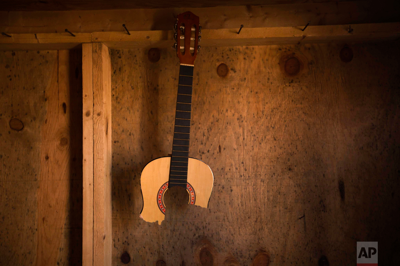 In this Thursday, Oct. 27, 2016 photo, a broken guitar hangs in an abandoned tent at the makeshift migrant camp known as "the jungle" near Calais, northern France. (AP Photo/Emilio Morenatti)