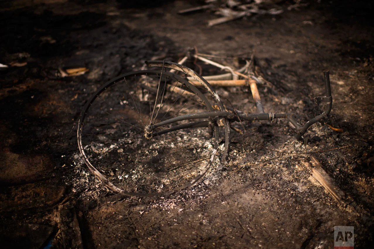 In this Thursday, Oct. 27, 2016 photo, a burnt bicycle remains on the floor of a charred tent at the makeshift migrant camp known as "the jungle" near Calais, northern France. (AP Photo/Emilio Morenatti)