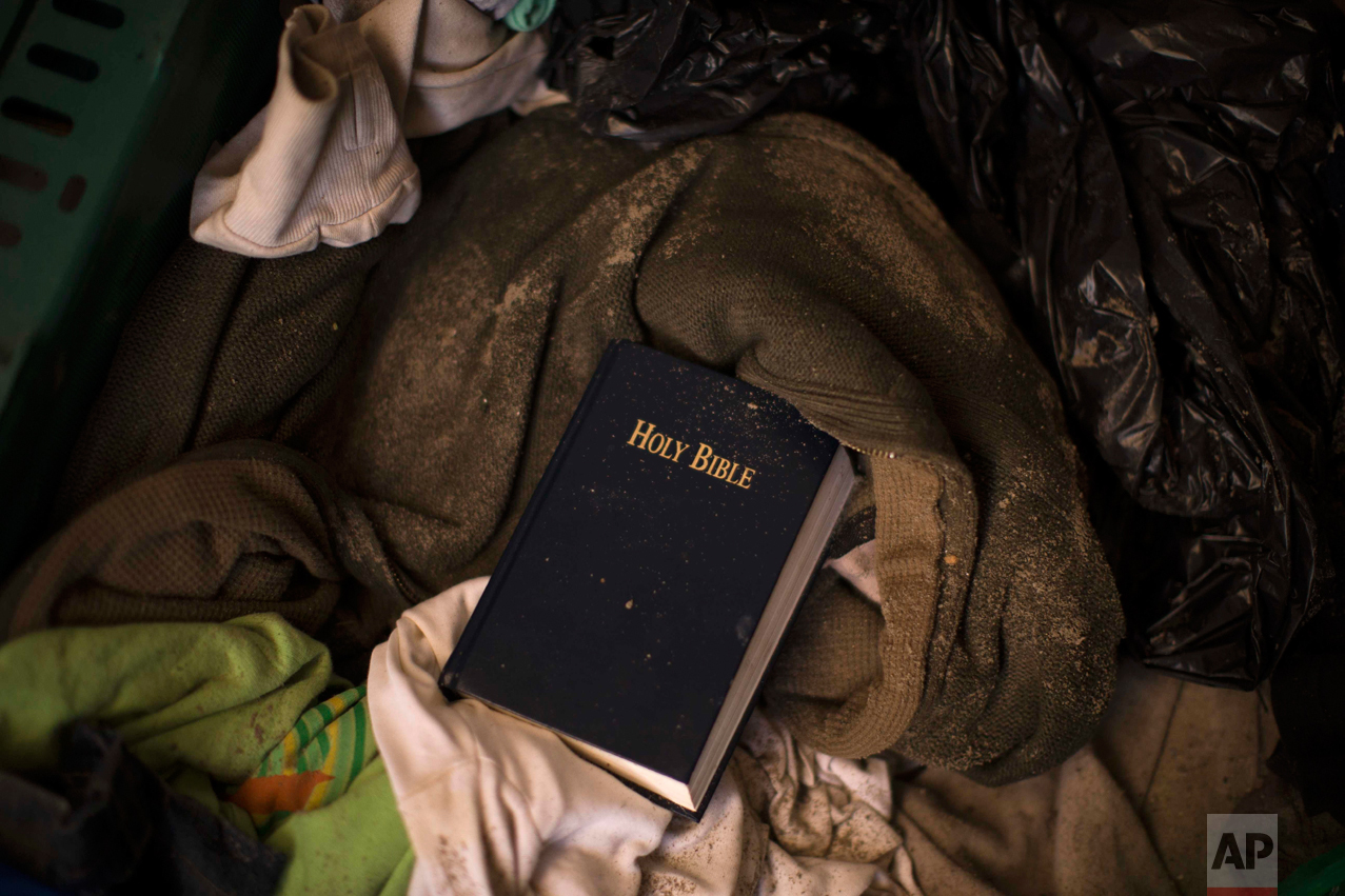 In this Thursday, Oct. 27, 2016 photo, a copy of the Bible remains over other belongings left behind by migrants, in an abandoned tent at the makeshift migrant camp known as "the jungle" near Calais, northern France. (AP Photo/Emilio Morenatti)
