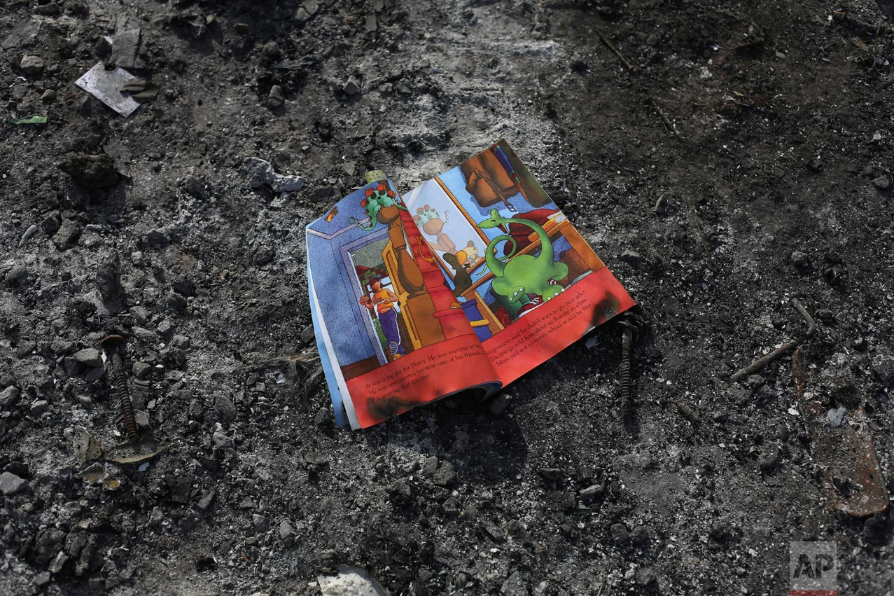 In this Thursday, Oct. 27, 2016 photo, a child's book left behind on the floor of a shelter by migrants in an abandoned tent at the makeshift migrant camp known as "the jungle" near Calais, northern France. (AP Photo/Thibault Camus)
