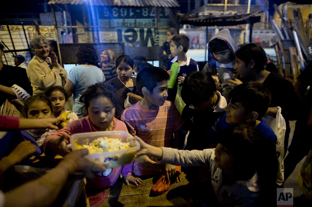 In this Oct. 13, 2016, children gather for free food given out by Norma Colque at her soup kitchen in the Villa 31 neighborhood of Buenos Aires, Argentina. "There's food for everyone. Don't worry," Colque said as she dumped ravioli into the containers that the families would carry back to their homes. But Colque worries that may not be true for long. (AP Photo/Natacha Pisarenko)