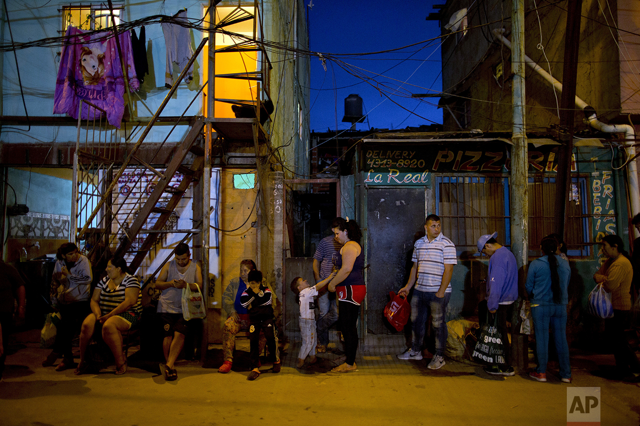 In this Oct. 13, 2016 photo, people line up outside Norma Colque's home to fill their containers with free food to take home to their families, outside the soup kitchen in the Villa 31 neighborhood of Buenos Aires, Argentina. Colque, who gets food from the state to serve about 200 a day, says that in recent months, she has had to stretch the pasta and stew because twice as many people are lining up for food. (AP Photo/Natacha Pisarenko)