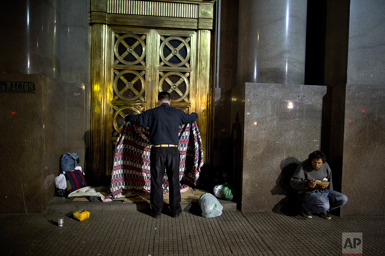 In this Oct. 5, 2016 photo, Alberto Cejas, who said he became homeless three years ago, prepares a place to sleep on a bed of cardboard outside the Senate Library in Buenos Aires, Argentina. As President Mauricio Macri campaigned last year, he often said his goal was to reach "zero poverty" by the end of his term in 2019. But when he released the poverty figures in late September, he said it's obvious it won't be possible. (AP Photo/Natacha Pisarenko)