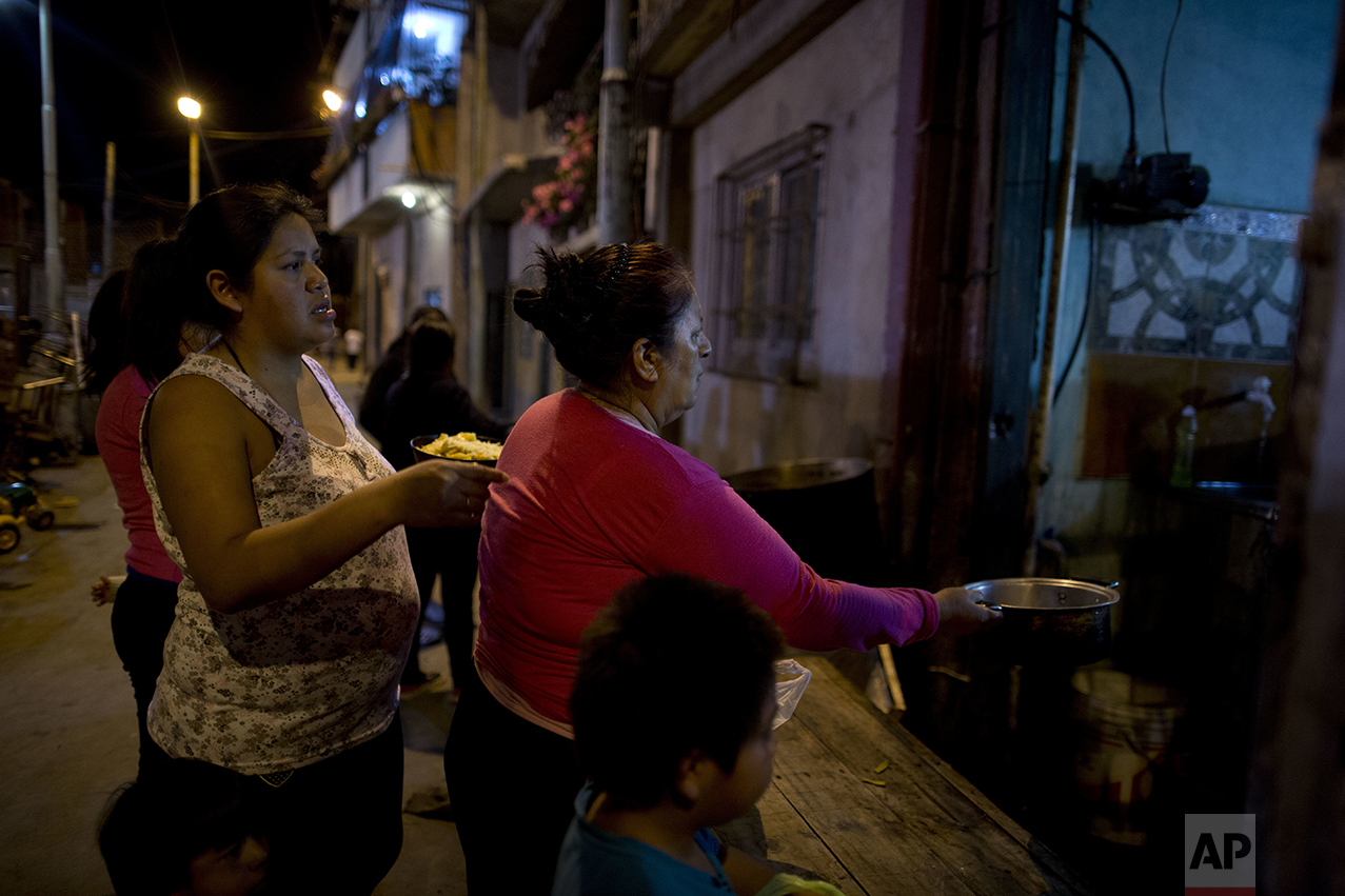 In this Oct. 13, 2016, women line up for a free dinner to take home to their families, from Norma Colque's soup kitchen in the Villa 31 neighborhood of Buenos Aires, Argentina. With the economy expected to shrink by 1.5 percent this year, President Mauricio Macri now admits his poverty goal isn't possible, and discontent is growing. (AP Photo/Natacha Pisarenko)