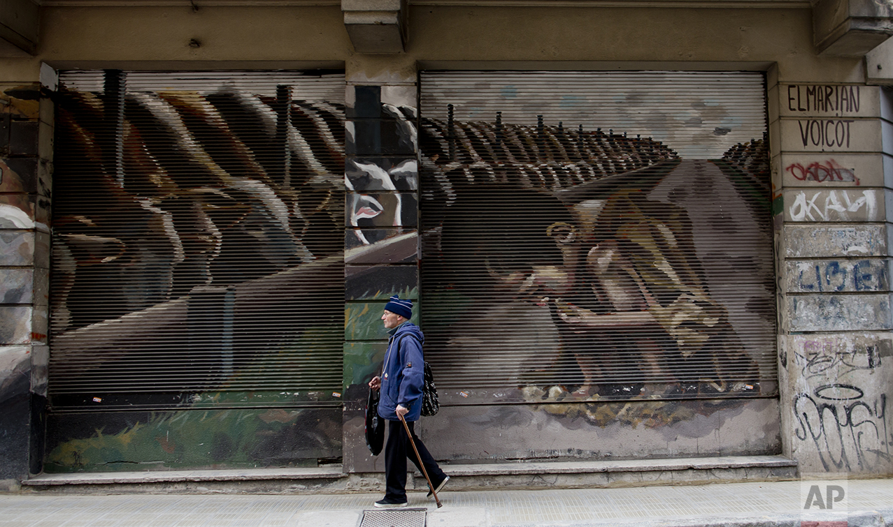 This Oct. 5, 2016 photo shows a mural titled "Hunger Games" by artist El Marian, featuring a starving boy huddling next to cattle eating grain in Buenos Aires, Argentina. The mural was an idea from animal rights group "Voicot" and aims to call attention to Argentina being one of the world's top grain producers, and that most of it is used to feed livestock. (AP Photo/Natacha Pisarenko)