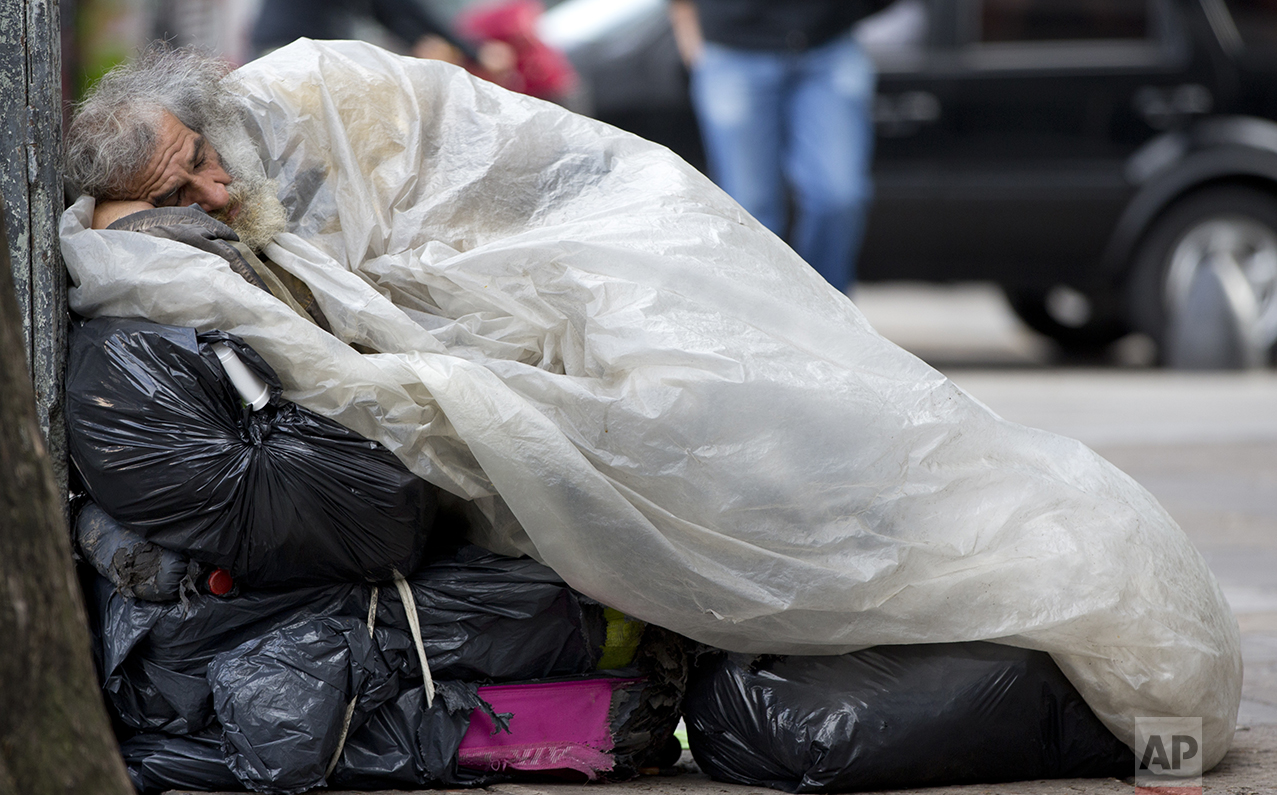 In this Oct. 3, 2016 photo, a homeless man sleeps on top of his belongings on the sidewalk, early in the morning in Buenos Aires, Argentina. The president of the World Bank recently praised President Mauricio Macri's efforts at providing clear data as a crucial step to reduce poverty. (AP Photo/Natacha Pisarenko)