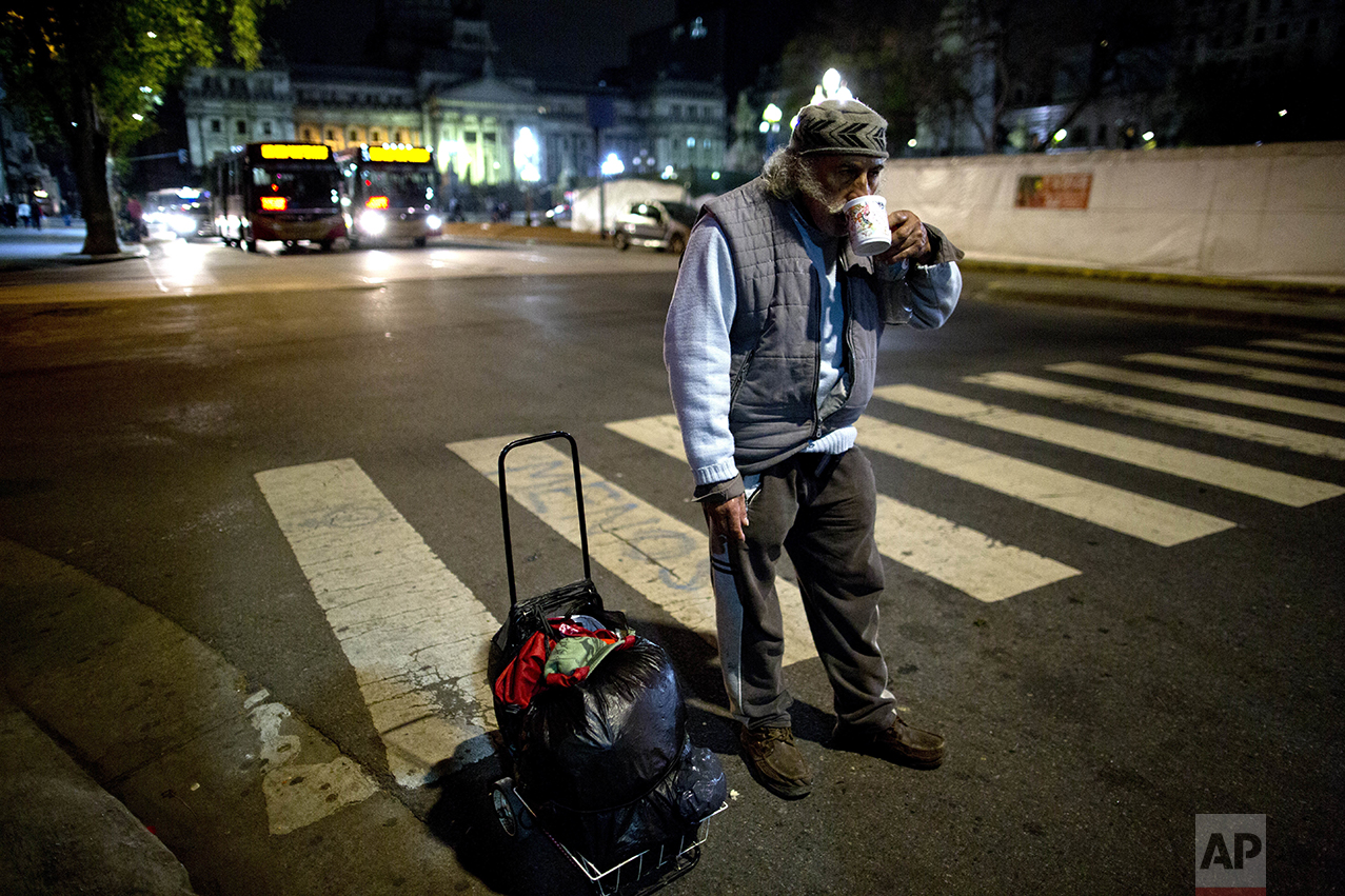 In this Oct. 5, 2016 photo, a homeless man drinks tea, given to him by a soup kitchen volunteer, in Buenos Aires, Argentina. The governments that took power since 2003 focused on rescuing Argentina from a devastating 2001 economic crisis that left one of every five Argentines out of work while some reported going hungry. Many economists are urging current President Mauricio Macri to continue his reforms, even if they are painful for now. (AP Photo/Natacha Pisarenko)