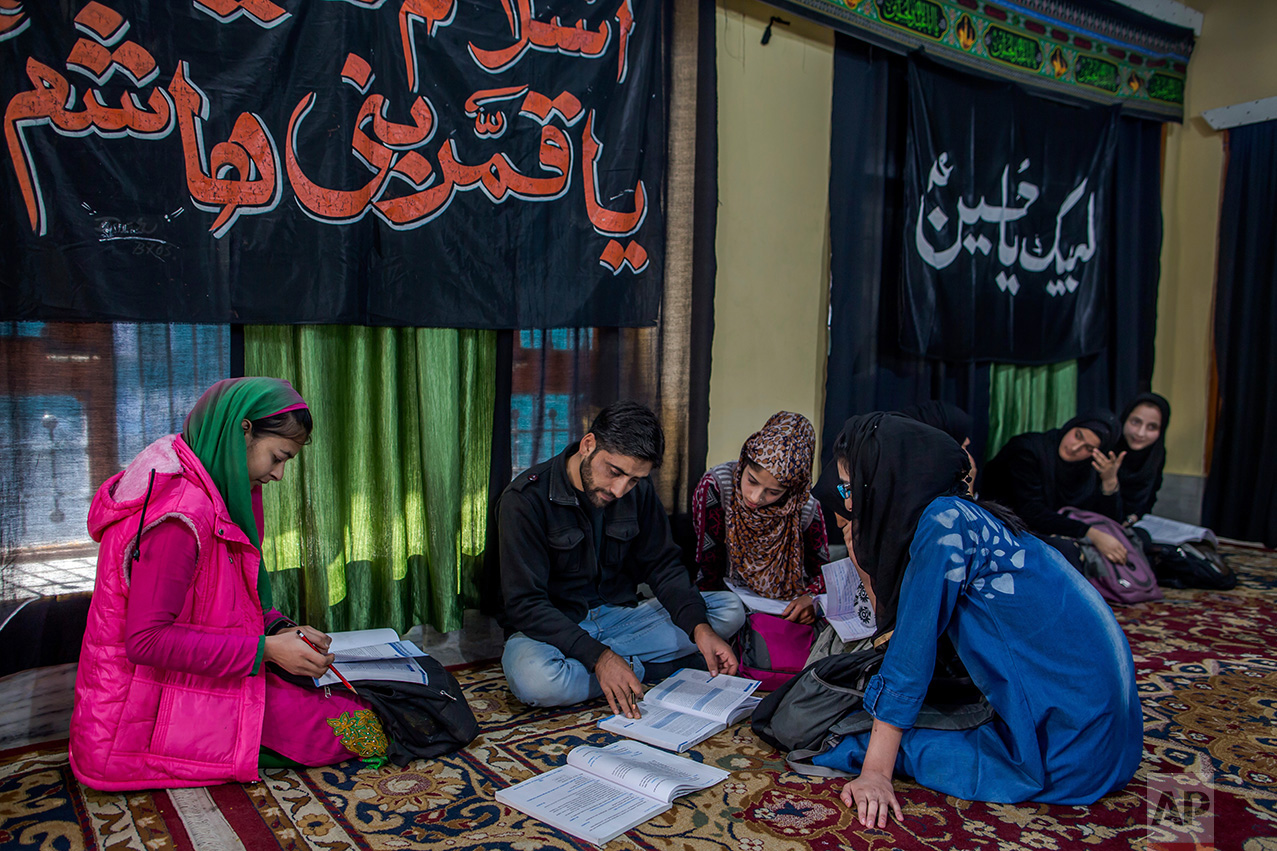 In this Wednesday, Oct. 19, 2016 photo, Mohammad Hussain teaches Kashmiri girls in an ad-hoc learning center set up in a building meant for religious activity in Srinagar, Indian controlled Kashmir. With daily life still paralyzed by strikes and rolling curfews, dozens of learning centers have popped up in people's homes or religious centers like mosques in Kashmir since August. They gather during daylight hours, often sitting on the floor, to hear a teacher read aloud from a text or practice mathematical equations in a shared notebook. (AP Photo/Dar Yasin)