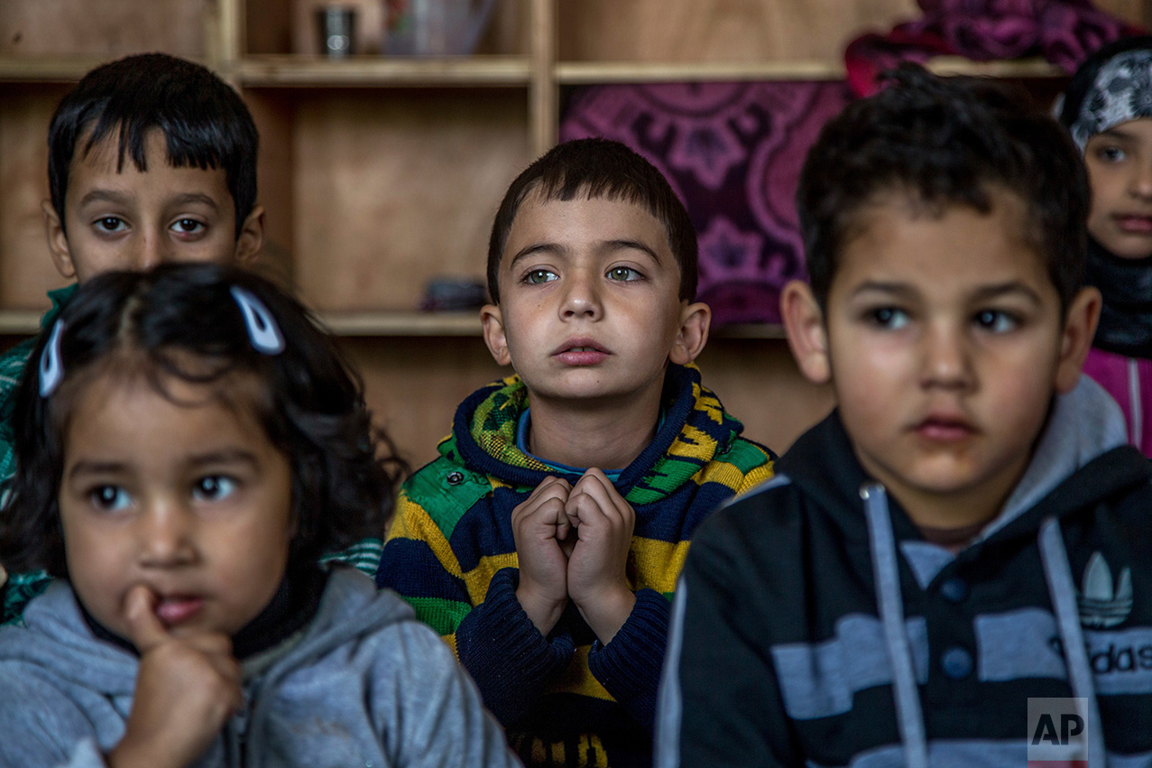 In this Thursday, Oct. 20, 2016 photo, Kashmiri children listen to their teacher as they attend an ad-hoc learning center at a local mosque in Srinagar, Indian controlled Kashmir. With daily life still paralyzed by strikes and rolling curfews, dozens of learning centers have popped up in people's homes or religious centers like mosques in Kashmir since August. The centers are doing more than just helping students prepare for upcoming exams, organizers said. They're keeping kids off the streets and giving them comfort amid a civilian uprising sparked when a popular rebel leader was killed in fighting Indian forces on July 8. (AP Photo/Dar Yasin)