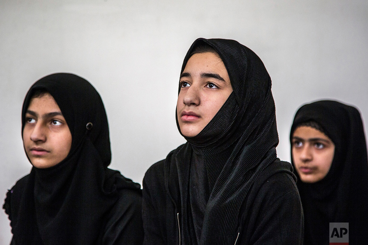 In this Thursday, Oct. 6, 2016 photo, Kashmiri girls attend an ad-hoc learning center set up in a community hall in Srinagar, Indian controlled Kashmir. With daily life still paralyzed by strikes and rolling curfews, dozens of learning centers have popped up in people's homes or religious centers like mosques in Kashmir since August. The centers are doing more than just helping students prepare for upcoming exams, organizers said. They’re keeping kids off the streets and giving them comfort amid a civilian uprising sparked when a popular rebel leader was killed in fighting Indian forces on July 8. (AP Photo/Dar Yasin)