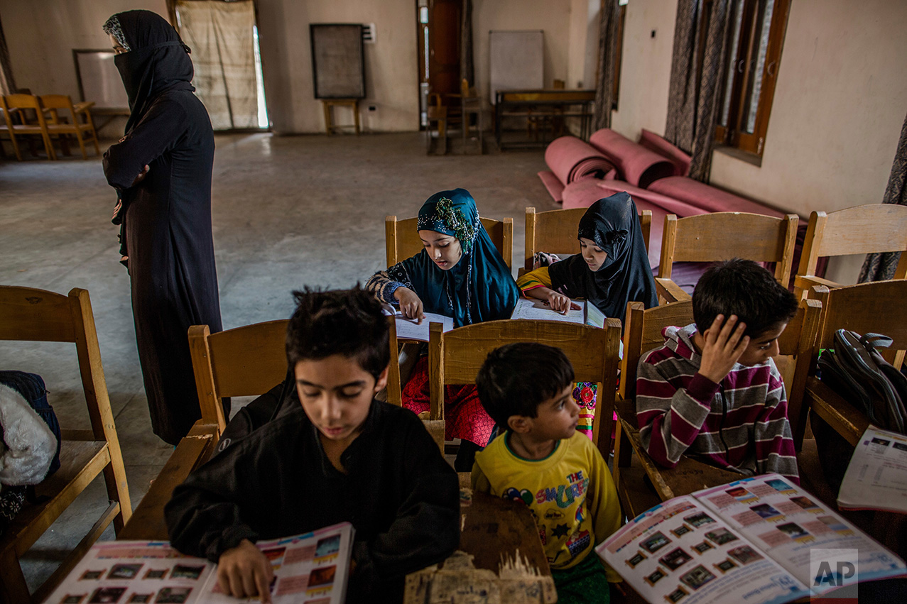 In this Friday, Oct. 7, 2016 photo, Kashmiri children attend an ad-hoc learning center set up in a community marriage hall in Srinagar, Indian controlled Kashmir. With daily life still paralyzed by strikes and rolling curfews, dozens of learning centers have popped up in people's homes or religious centers like mosques in Kashmir since August. The centers are doing more than just helping students prepare for upcoming exams, organizers said. They’re keeping kids off the streets and giving them comfort amid a civilian uprising sparked when a popular rebel leader was killed in fighting Indian forces on July 8. (AP Photo/Dar Yasin)