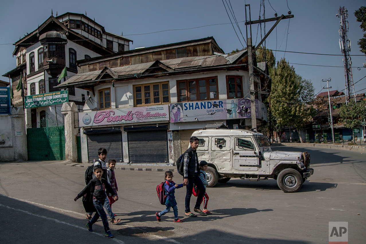 In this Friday, Oct. 21, 2016 photo, Kashmiri children walk home after attending private classes, on a deserted street during curfew in Srinagar, Indian controlled Kashmir. With daily life still paralyzed by strikes and rolling curfews, dozens of ad-hoc learning centers have popped up in people's homes or religious centers like mosques in Kashmir since August. (AP Photo/Dar Yasin)