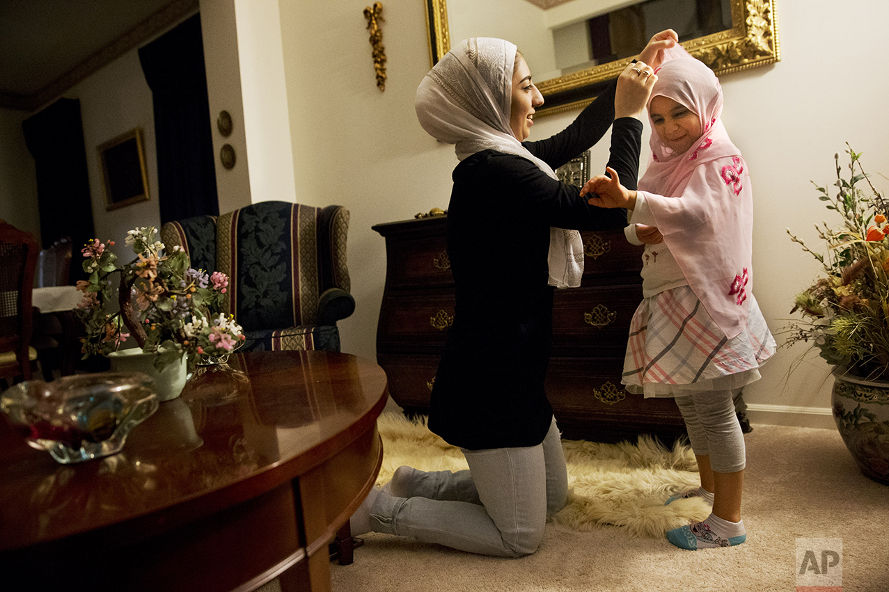 Hannah Shraim, 17, left, fixes a scarf around Lana Algamil, 5, after the little girl asked Hannah if she could try one on before evening prayers at the Shraim family home in Germantown, Md., Friday, May 6, 2016. (AP Photo/Jacquelyn Martin)