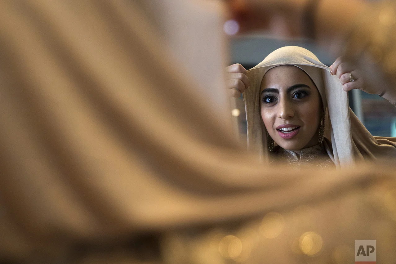 Hannah Shraim, 17, affixes her hijab that she bought to match a special prom dress she ordered from a Turkish website that specializes in modest fashion, as she prepares to attend Northwest High School's senior prom, in Germantown, Md., on Friday, May 13, 2016. (AP Photo/Jacquelyn Martin)