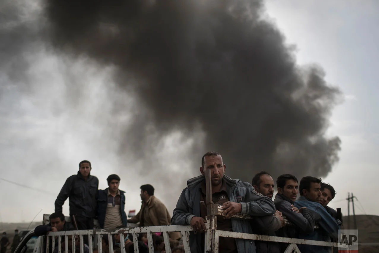 Displace people stand on the back of a truck at a checkpoint near Qayara, south of Mosul, Iraq, Tuesday, Nov. 1, 2016. The U.N. human rights office is lauding efforts by the U.S.-led coalition in the battle against the Islamic State group in Mosul. The office in Geneva says coalition flights over Iraq have largely succeeded in preventing IS from bringing in 25,000 more civilians to the city center, where the militant group has been using people as human shields as Iraqi forces advance on Mosul. (AP Photo/Felipe Dana)