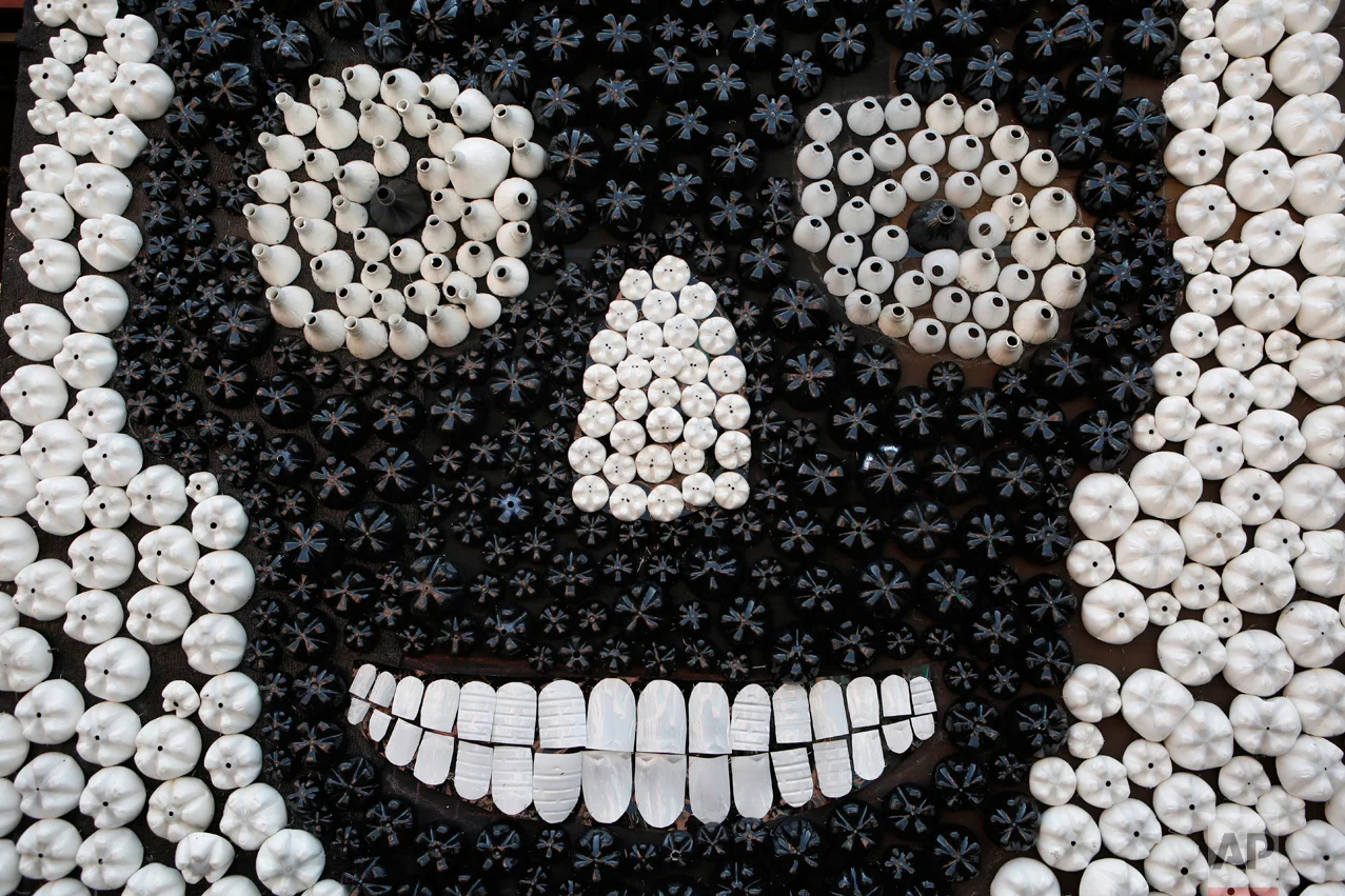 Scavenged plastic bottles form a sugar skull as part of a competition to create Day of the Dead altars on pedestrian Regina Street in central Mexico City, Tuesday, Nov. 1, 2016. The holiday honors the dead as friends and families gather in cemeteries to decorate their loved ones' graves and hold vigil through the night on Nov. 1 and 2. (AP Photo/Rebecca Blackwell)
