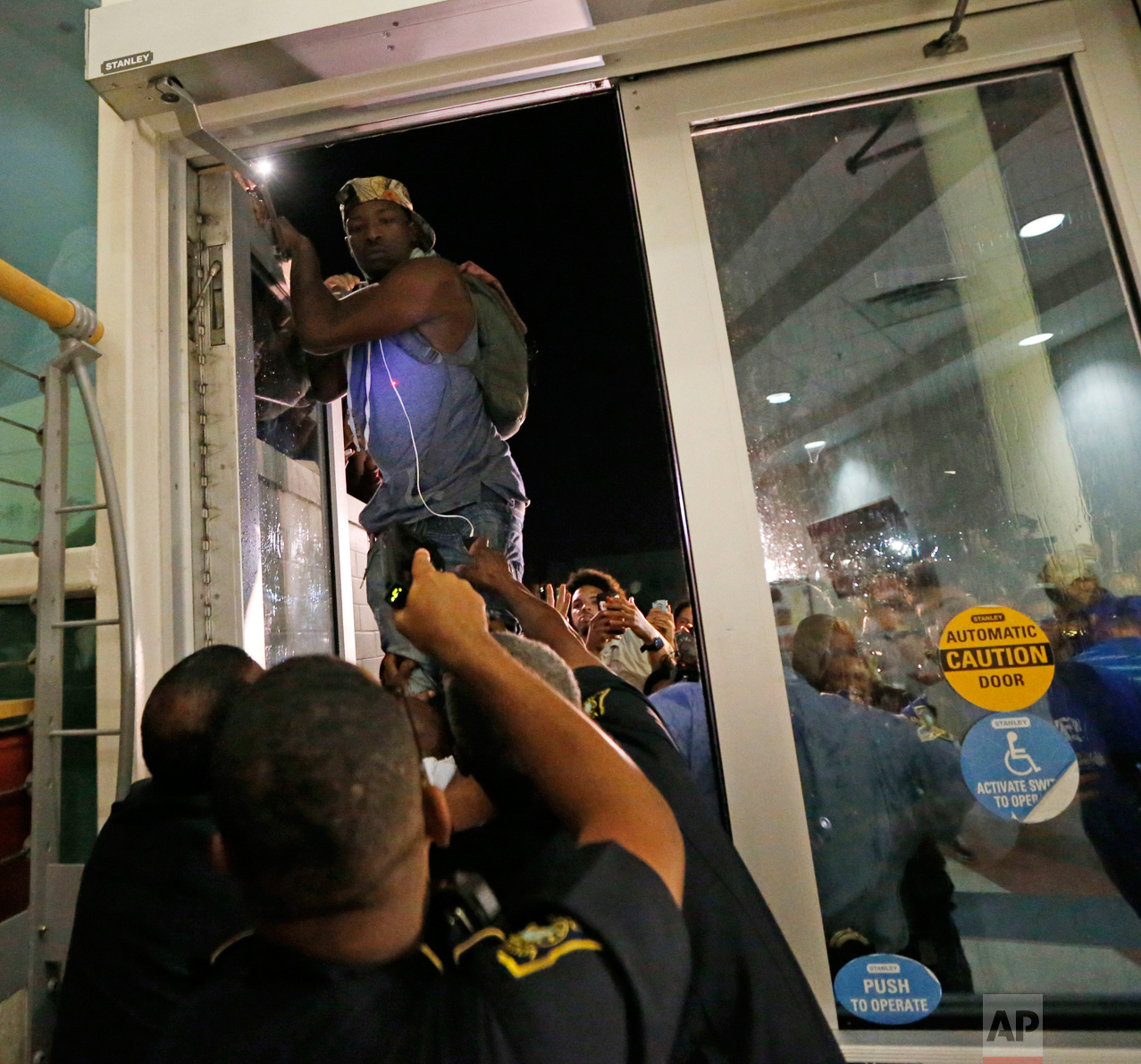  A police officer, front, points a taser as a protester jumps on a door, whole police officers try to keep out protesters against the former Ku Klux Klan leader and current senate candidate David Duke, before a debate for Louisiana candidates for the