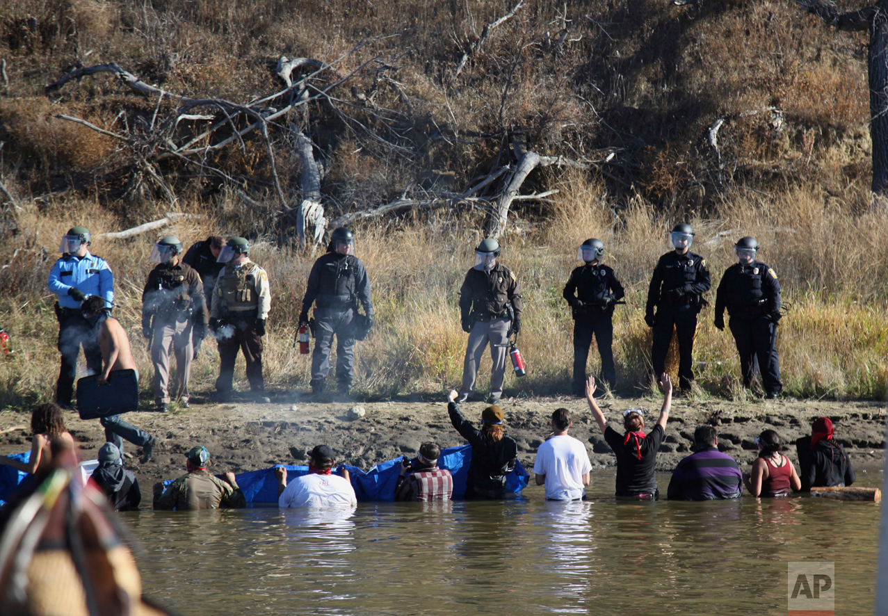  Dozens of protestors demonstrating against the expansion of the Dakota Access Pipeline wade in cold creek waters confronting local police, as remnants of pepper spray waft over the crowd near Cannon Ball, N.D., Wednesday, Nov. 2, 2016. Officers in r