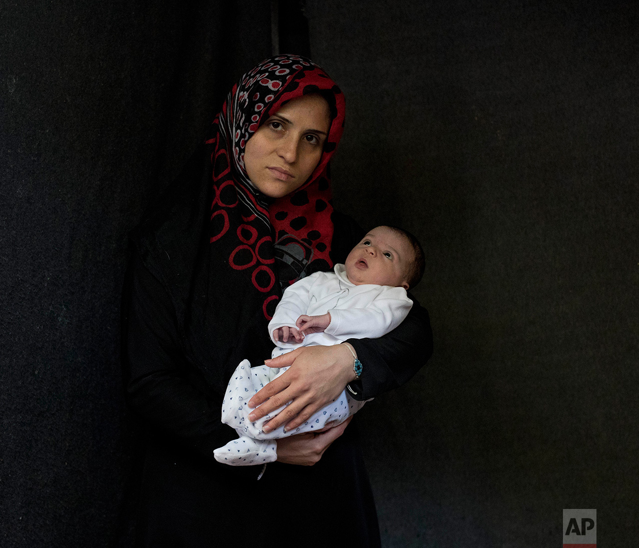 In this Saturday, Oct. 29, 2016 photo 27-year-old Nofa Bashar, a Syrian mother from Aleppo, poses with her baby girl Evelina Bashar in a tent made of blankets given by UNCHR at the Ritsona refugee camp in Greece. Nofa is one of the hundreds of refug