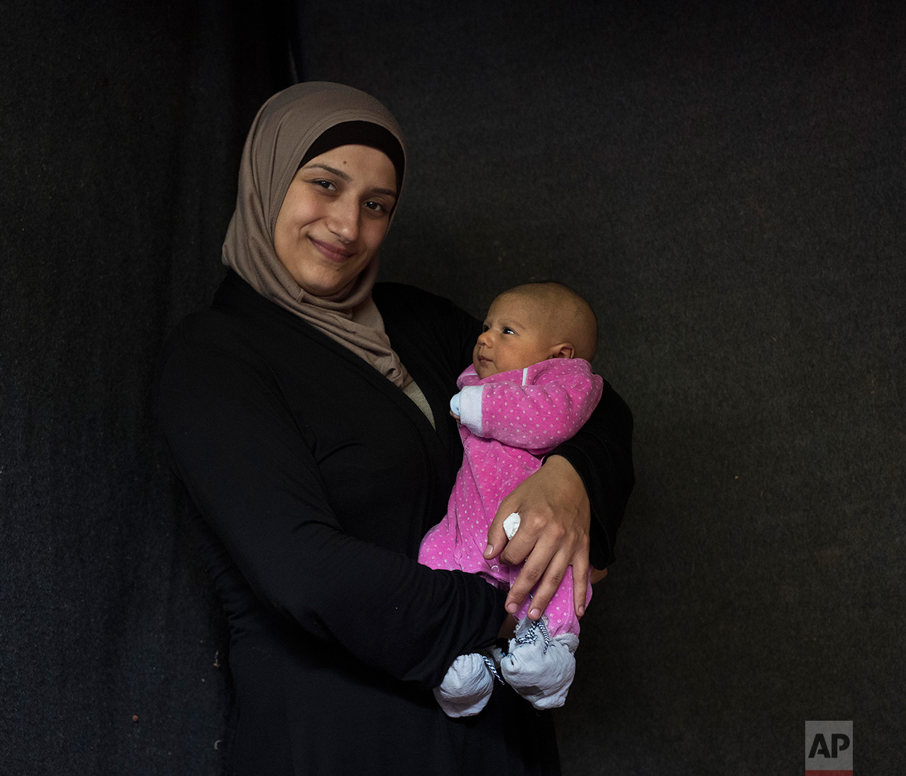  In this Wednesday Oct.12, 2016 photo 28-year-old Hala Baroud, a Syrian mother from Latakia, poses with her baby girl Farah in a tent made of blankets given by the UNCHR at the Ritsona refugee camp in Greece. Hala is one of the dozens of refugee wome