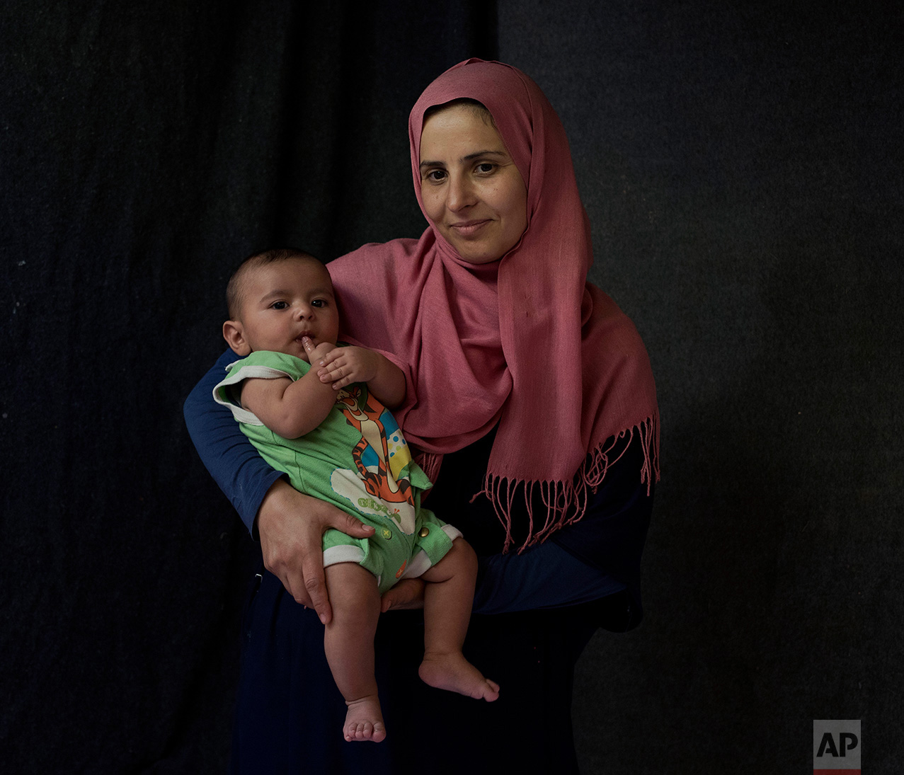  In this Tuesday Sept. 13, 2016, 39-year-old, Hanan Halawa, a Syrian mother from the city of Idlib poses with her baby boy Ahmad Hanash in a tent made of blankets given by the UNCHR at the Ritsona refugee camp in Greece. Hanan is one of the hundreds 