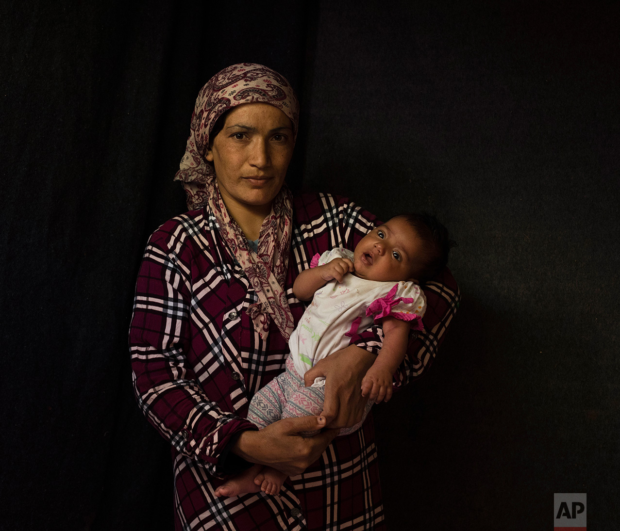  In this Tuesday Sept. 13, 2016 photo 33-year-old Kaouser Tamo, a Syrian mother from Al Hasakah, poses with her baby girl Shidra Abdul Gani Ahmed in a tent made of blankets given by the UNCHR at the Ritsona refugee camp in Greece. Kaouser is one of t