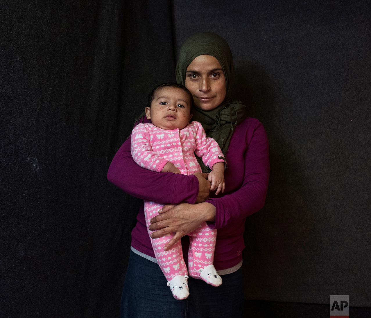 In this Wednesday Oct. 19, 2016, 25-year-old Arna Al Mousa, a Syrian mother from the city of Idlib, poses with her baby boy Yousef Al Mousa in a tent made of blankets given by the UNCHR at the Ritsona refugee camp in Greece. Anna is one of the hundr