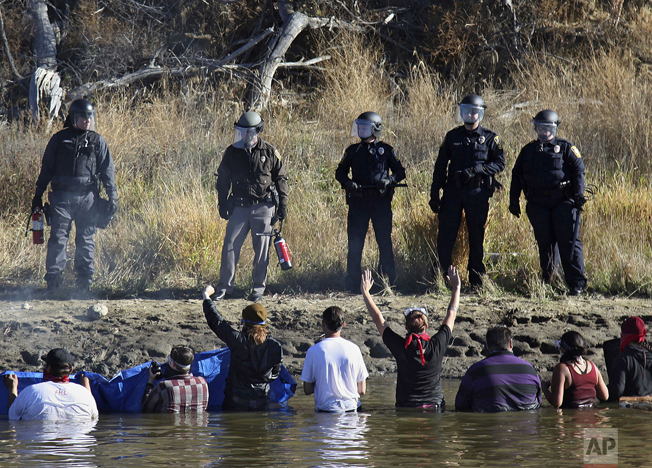  Dozens of protestors demonstrating against the expansion of the Dakota Access Pipeline wade in cold creek waters confronting local police, as remnants of pepper spray waft over the crowd near Cannon Ball, N.D., Wednesday, Nov. 2, 2016. (AP Photo/Joh