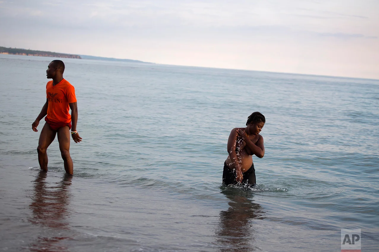 In this Oct. 31, 2016 photo, Nathanaelle Bernard, 7 months pregnant, bathes in the sea waters, the most relaxing part of her day, in Coteaux, Haiti. Nathanaelle was two months short of the due date for her first child when Hurricane Matthew crashed through Coteaux, destroying her small home of cinder blocks and carrying away most of her belongings. "We lost the things we had. But we're not lost," she said after drying herself off on the sandy beach. (AP Photo/Dieu Nalio Chery)
