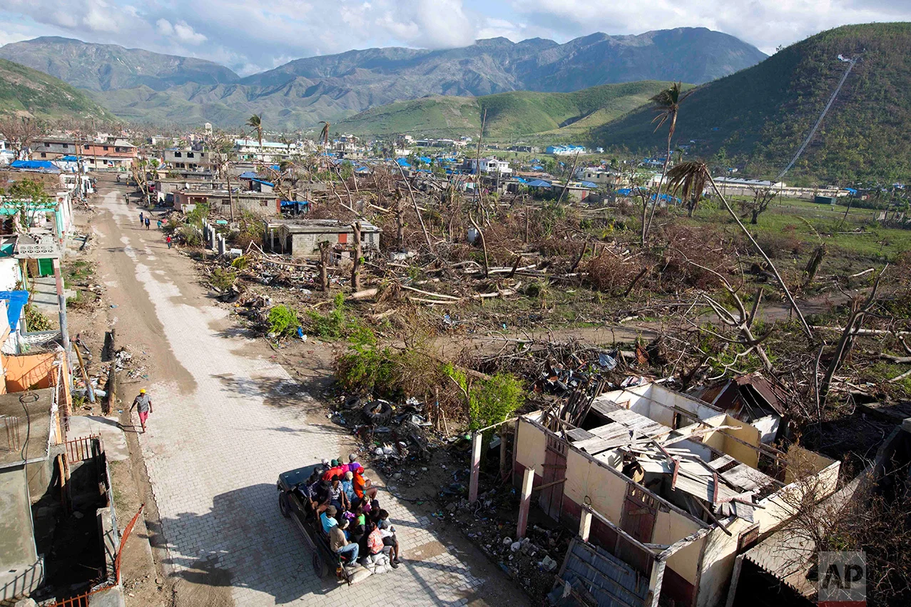 In this Nov. 1, 2016 photo, vendors are transported in a "tap-tap" past a landscape of destruction, caused by Hurricane Matthew, in Coteaux, Haiti. Many experts fear the advances Haiti made, have been rolled back by the storm, which made landfall on the peninsula on Oct. 4, with 145 mph winds. (AP Photo/Dieu Nalio Chery)