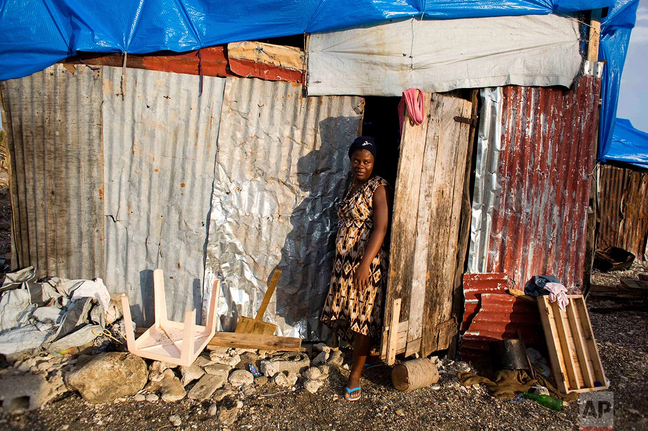 In this Oct. 31, 2016 photo, Nathanaelle Bernard, who is 7 months pregnant, steps outside from a makeshift hut where she now lives, after her home was destroyed by Hurricane Matthew, in Coteaux, Haiti. The 19-year-old is among the nearly 14,000 women who are due to give birth in the coming weeks amid widespread shortages of food, water and housing. (AP Photo/Dieu Nalio Chery)