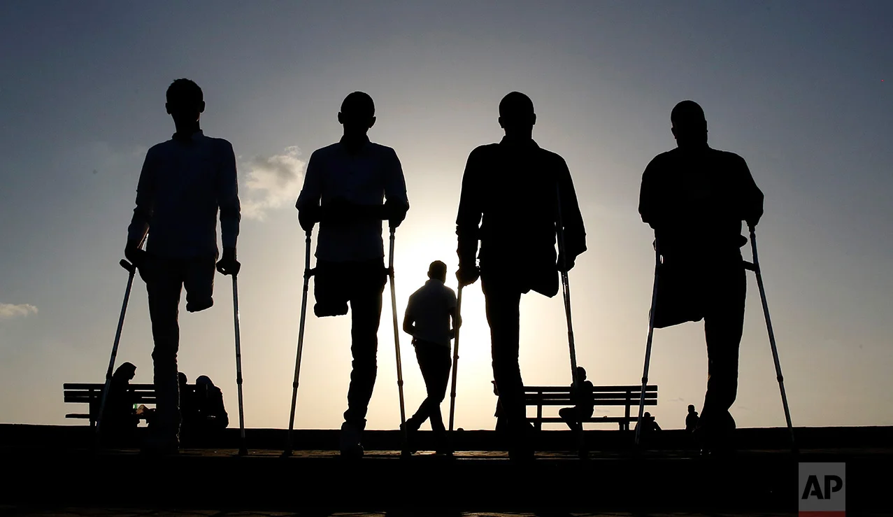Four Palestinian friends who were injured during conflicts walk by the sea at Gaza's small fishing harbor, Monday, Oct. 24, 2016. Fighting left thousands of people with disabilities or no limbs in this Palestinian enclave. (AP Photo/Hatem Moussa)