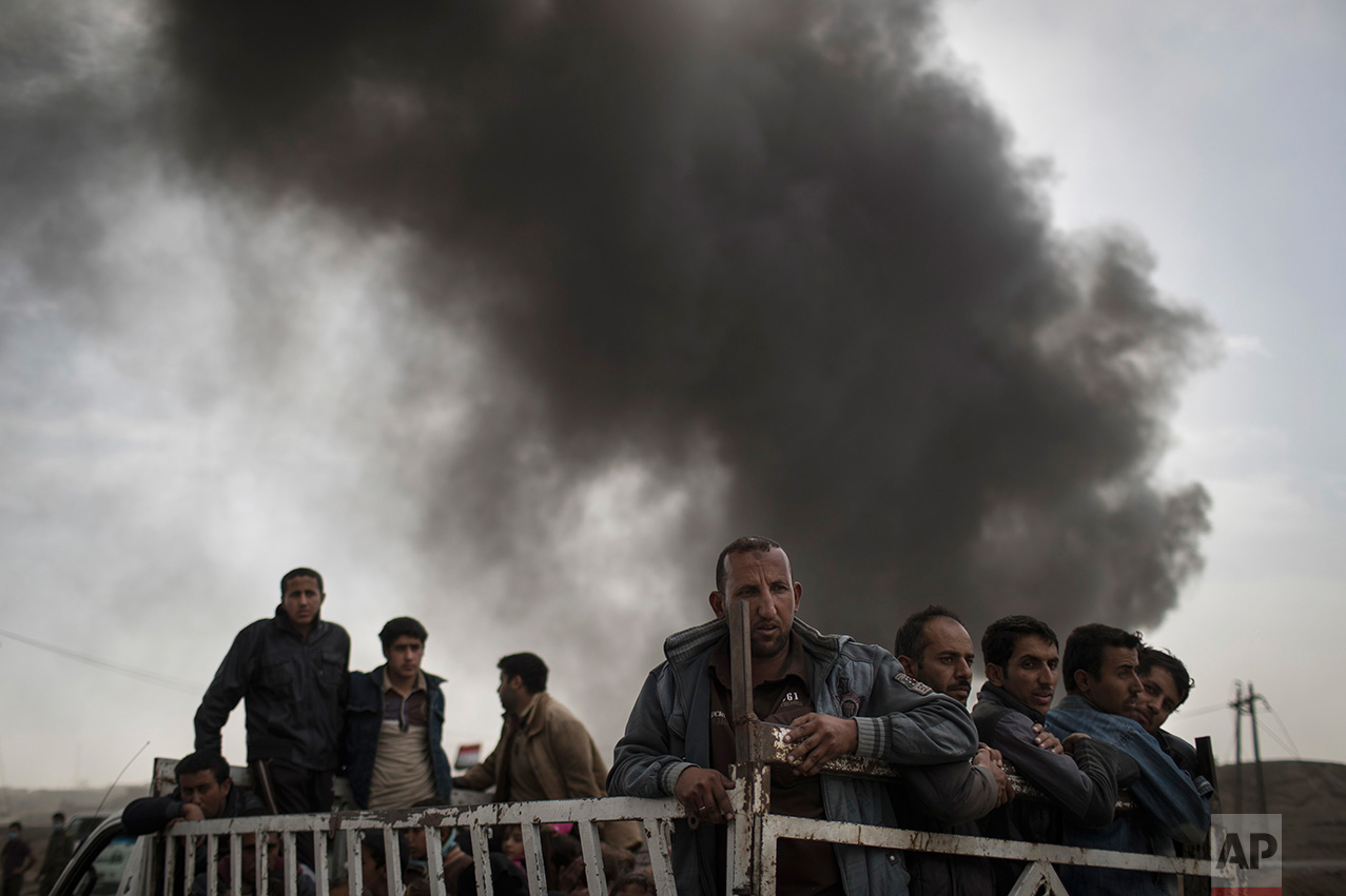 Displaced people stand on the back of a truck at a checkpoint near Qayara, south of Mosul, Iraq, Tuesday, Nov. 1, 2016. The UN human rights office is lauding efforts by the U.S.-led coalition in the battle against the Islamic State group in Mosul. The office in Geneva says coalition flights over Iraq have largely succeeded in preventing IS from bringing in 25,000 more civilians to the city center, where the militant group has been using people as human shields as Iraqi forces advance on Mosul. (AP Photo/Felipe Dana)